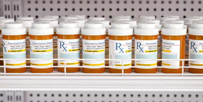 Row of prescription bottles on pharmacy shelf